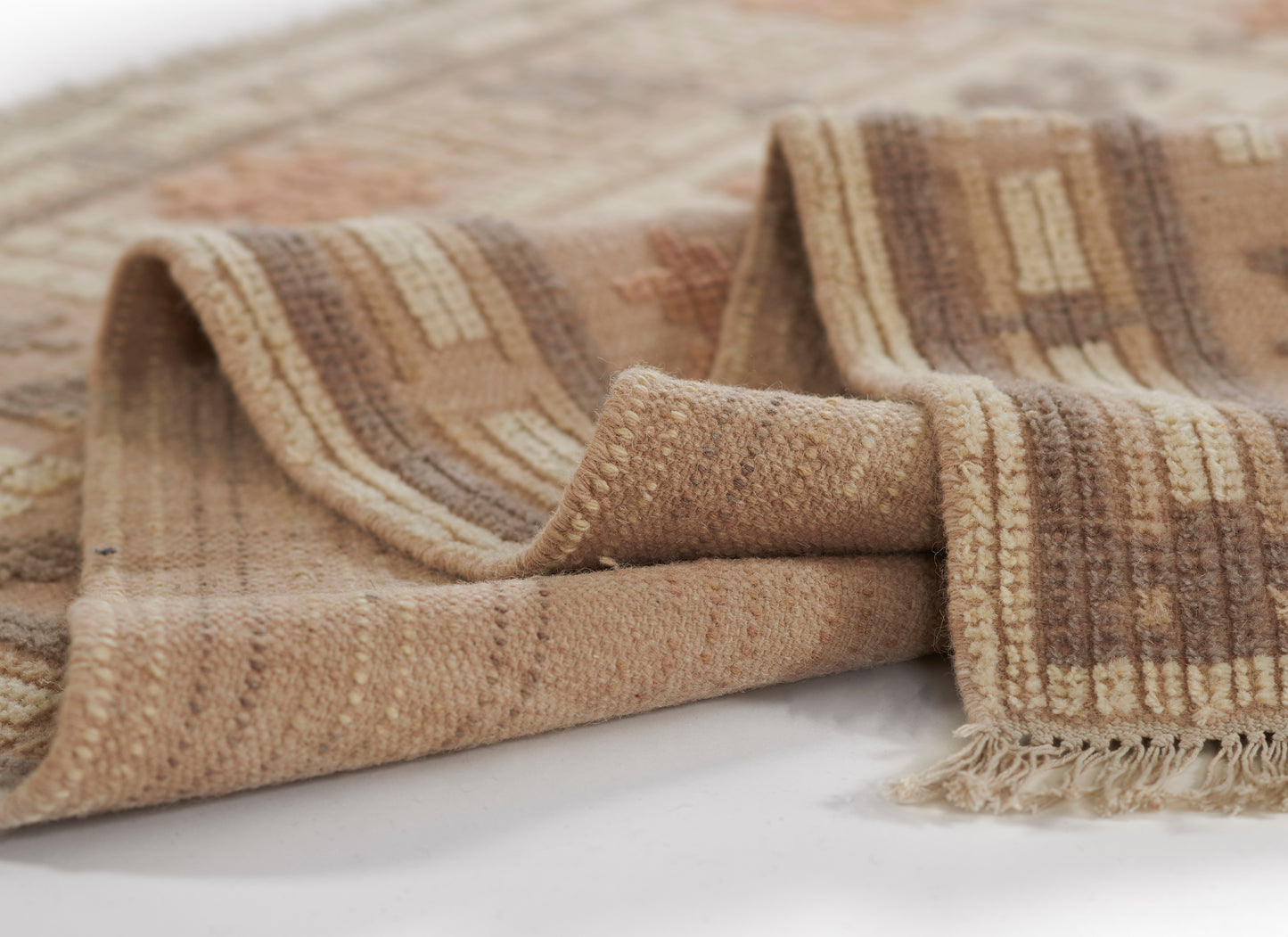 Beige, tan and brown striped woven rug with fringed edges and soft texture.