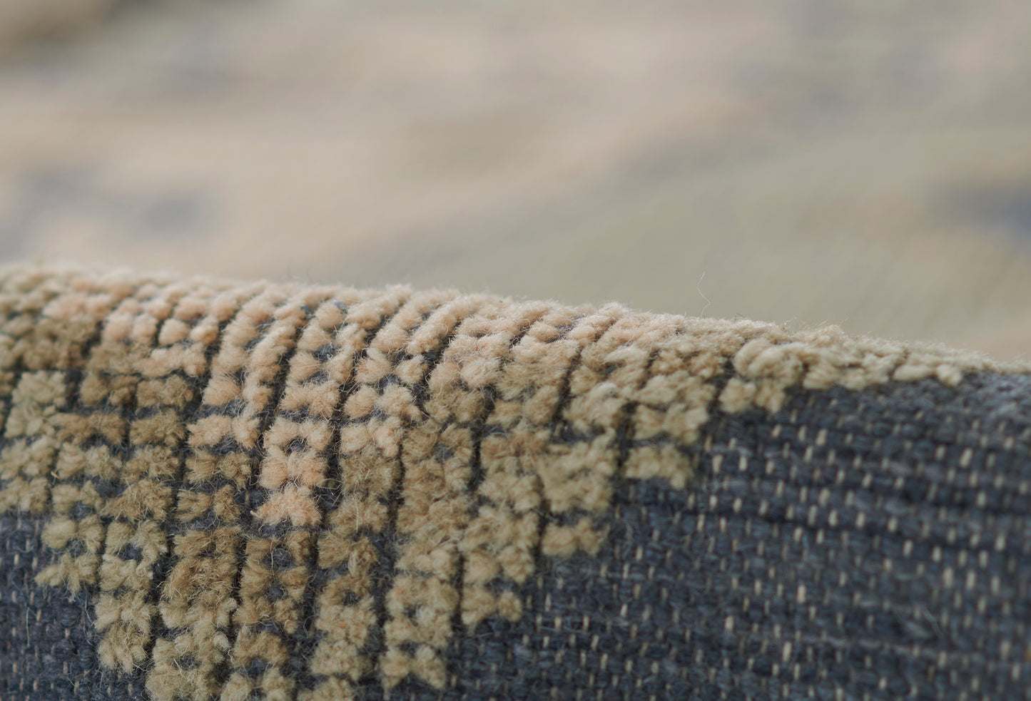 Close-up of a navy blue woven rug with tan textured pile pattern along the edge.
