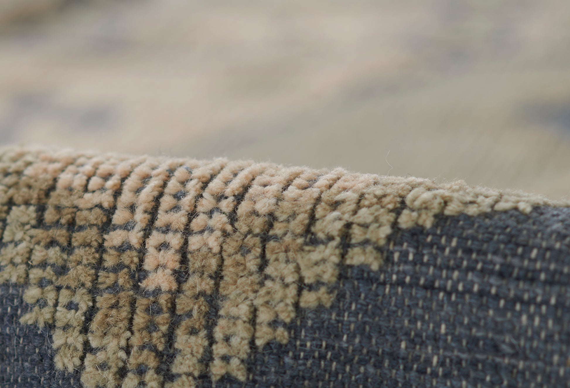 Close-up of a navy blue woven rug with tan textured pile pattern along the edge.