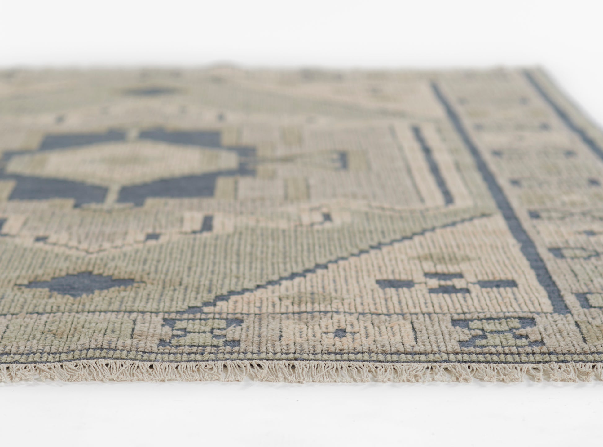 Beige and navy geometric rug, flat-weave with fringe edge, kilim-inspired pattern in a woven wool/cotton blend.