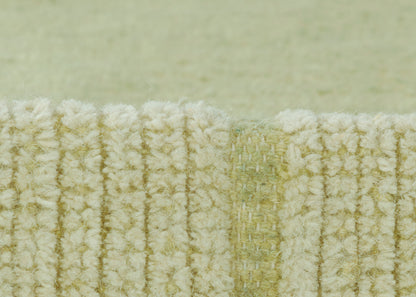 Close-up of pale green looped rug edge with cream fibers and ribbed texture.