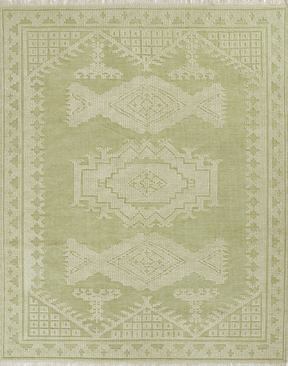 Olive green woven rug with cream geometric medallions, intricate border and fringed edges; tribal-style decor.