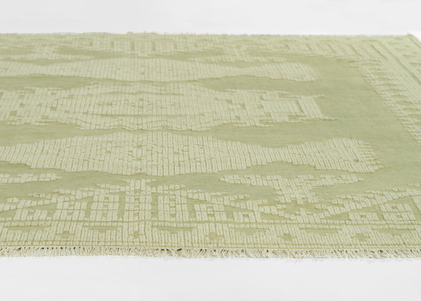 Sage-green rug with subtle cream geometric pattern and fringed edge.