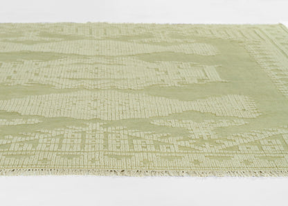 Sage-green rug with subtle cream geometric pattern and fringed edge.