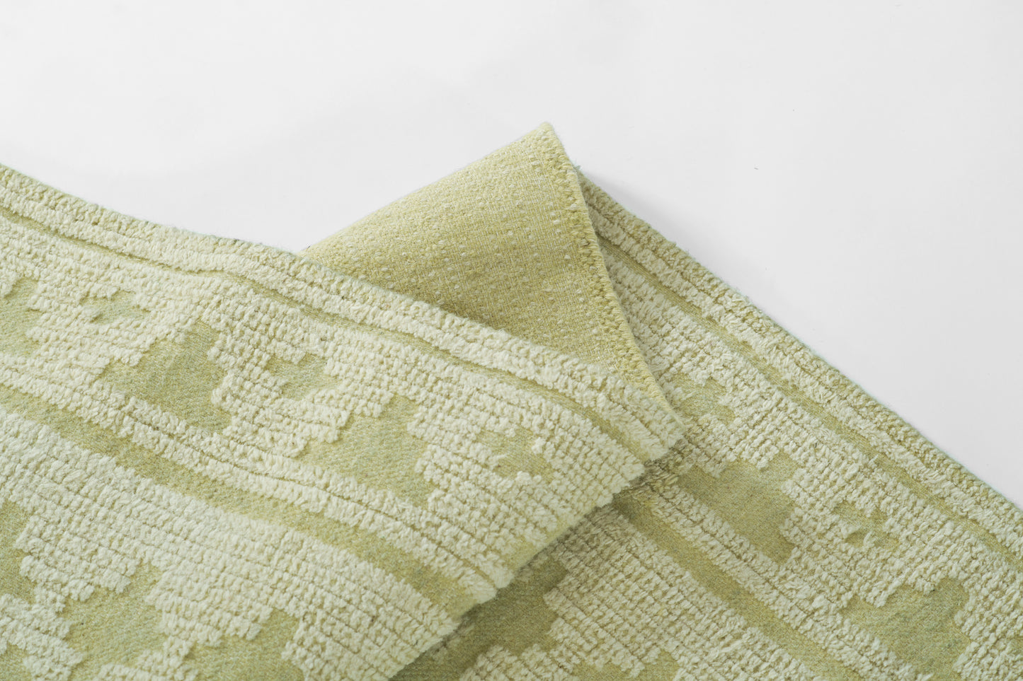 Soft sage green towel with cream textured jacquard border; plush terry, folded.