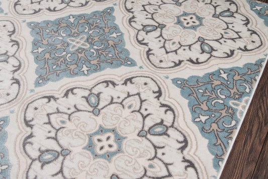 Persian-style rug with ivory and teal-blue medallions, intricate floral damask pattern on wood floor.