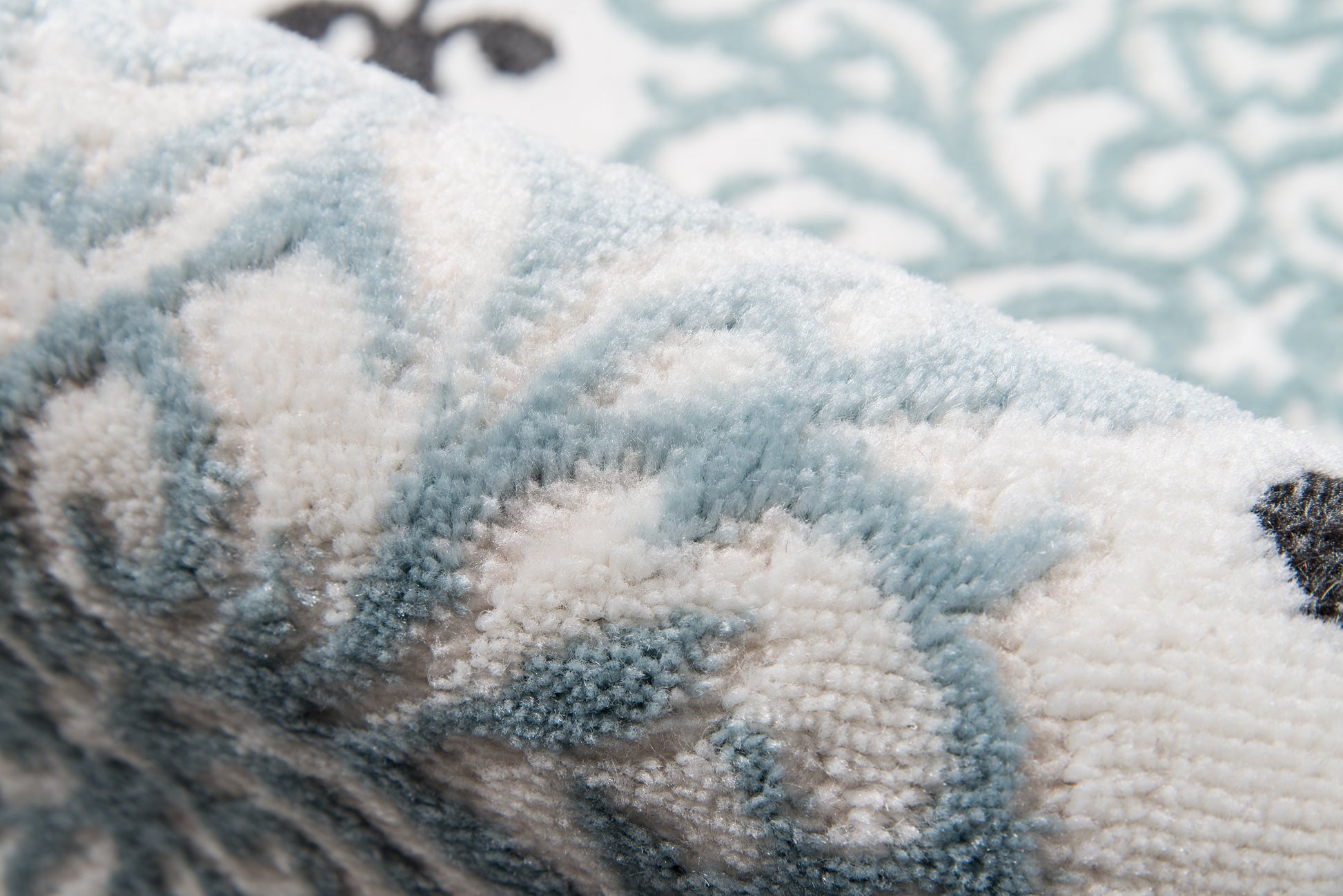Close-up of a blue and white high-pile plush rug with ornate scroll pattern.