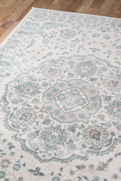 Ivory rug with teal floral and medallion pattern on a wooden floor.