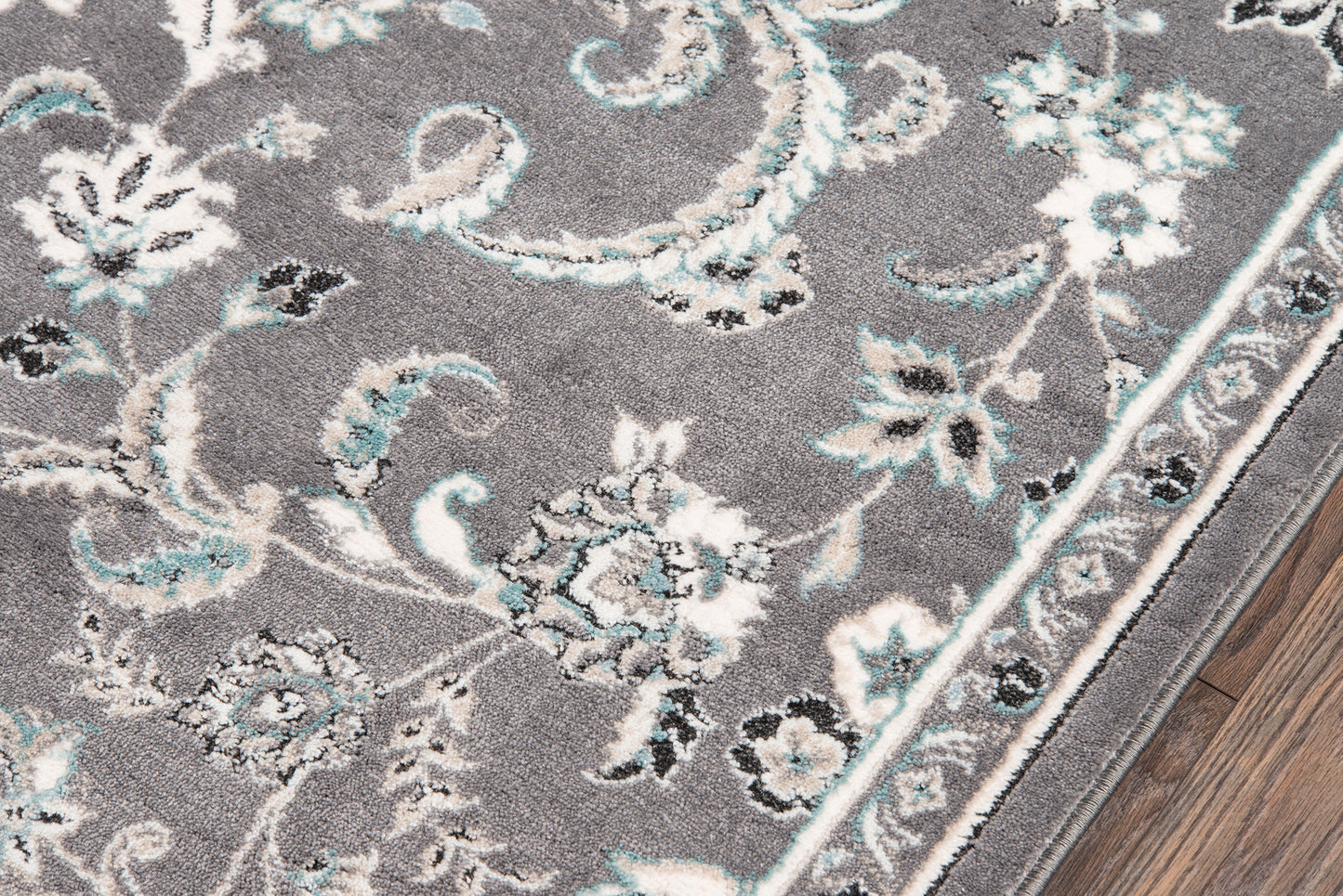 Rectangular gray ornate floral area rug with white and turquoise accents and a decorative border on a wood floor, size 9' x 13'.