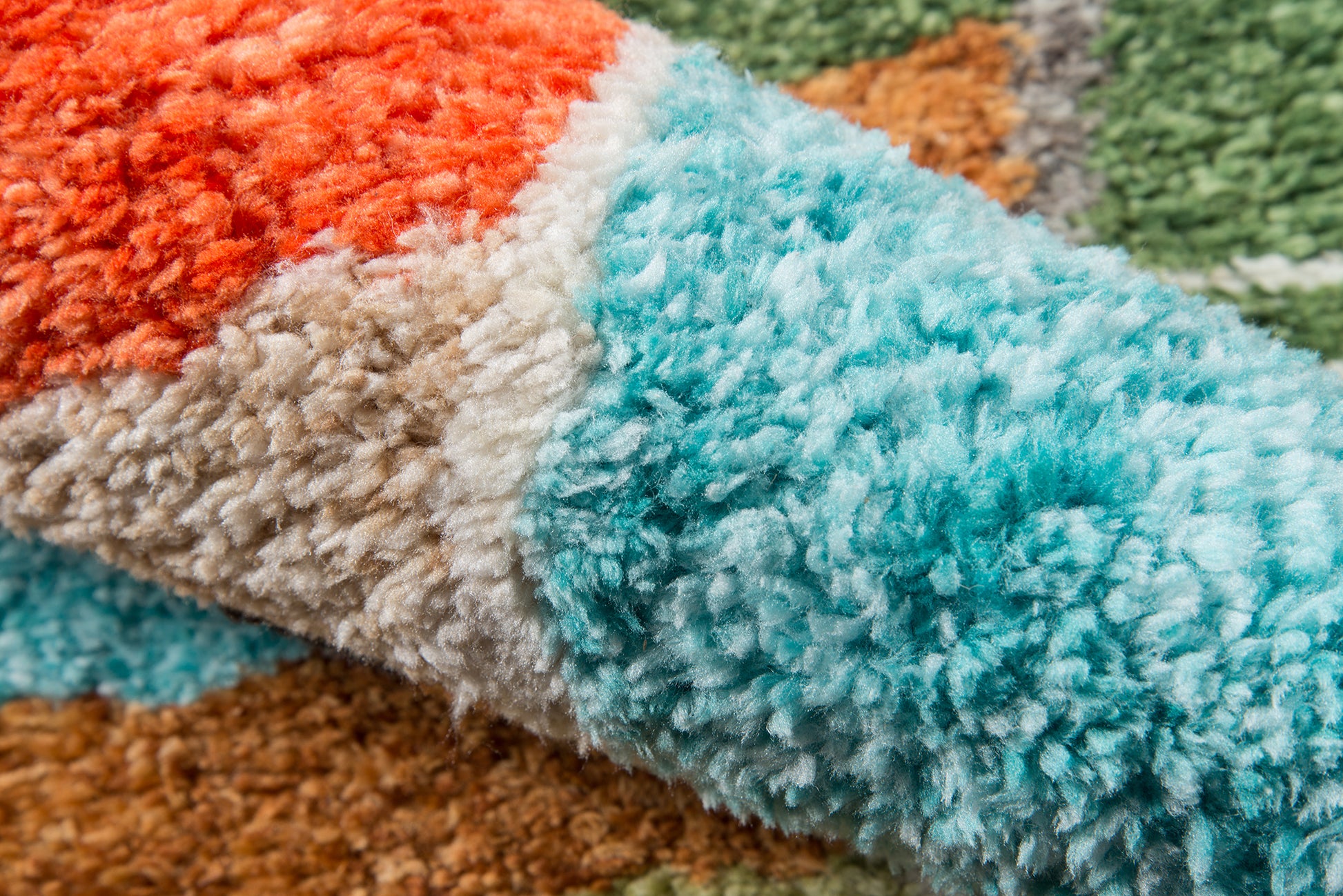 Close-up of a multicolored fluffy shag rug with teal, orange, beige and brown tufted fibers.