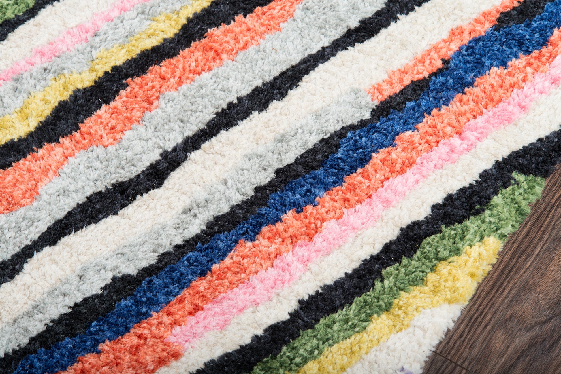 Shaggy, multicolor striped area rug with plush pile in cream, black, pink, orange, blue, green, and yellow.