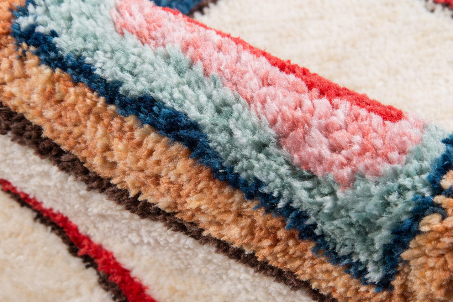 Soft shag rug with plush pile in pastel rainbow stripes: pink, mint, teal, brown, tan, cream.