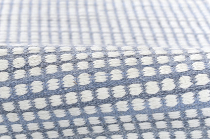 Blue woven rug with white tufted dots in a grid pattern; soft textured home decor.