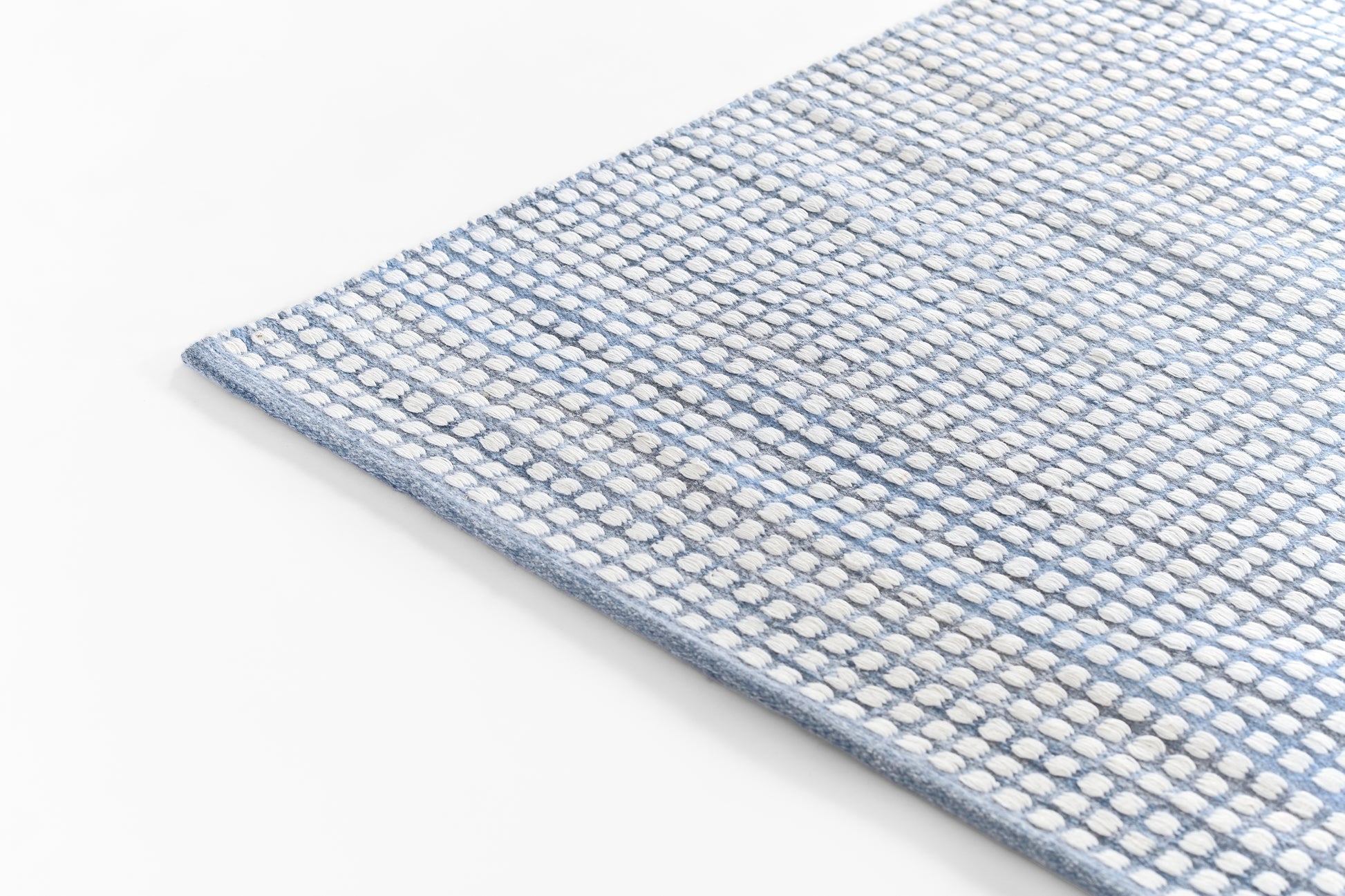 Blue and white woven rug with a dotted pattern and blue edge; rectangular loop-pile texture.