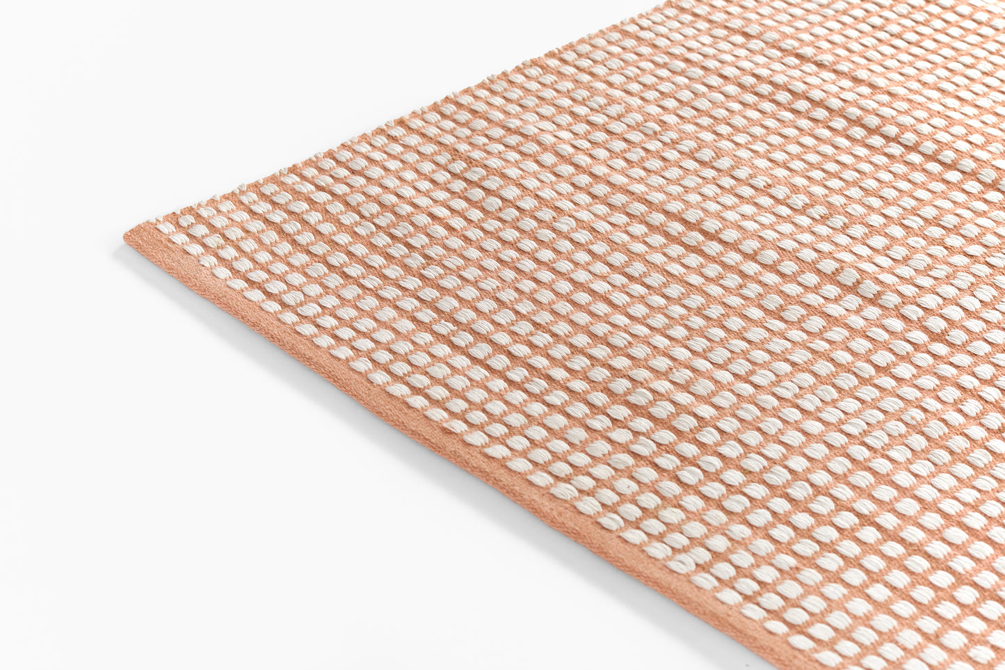 Rose-pink textured looped-pile runner rug with white dot pattern and peach border.