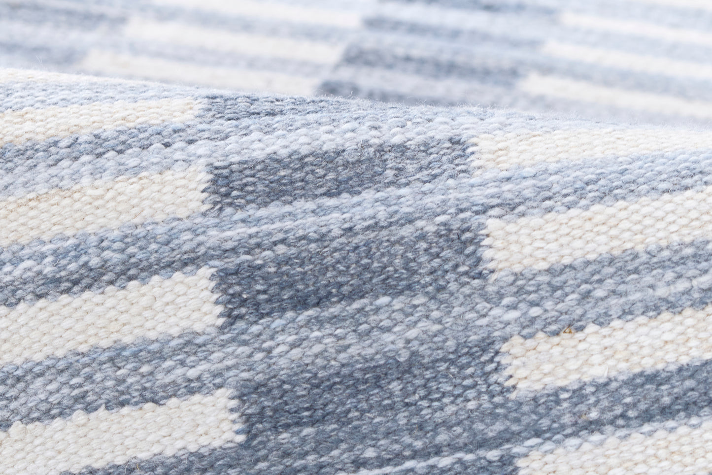 Blue-gray and cream striped chunky-knit blanket throw, close-up of woven texture.