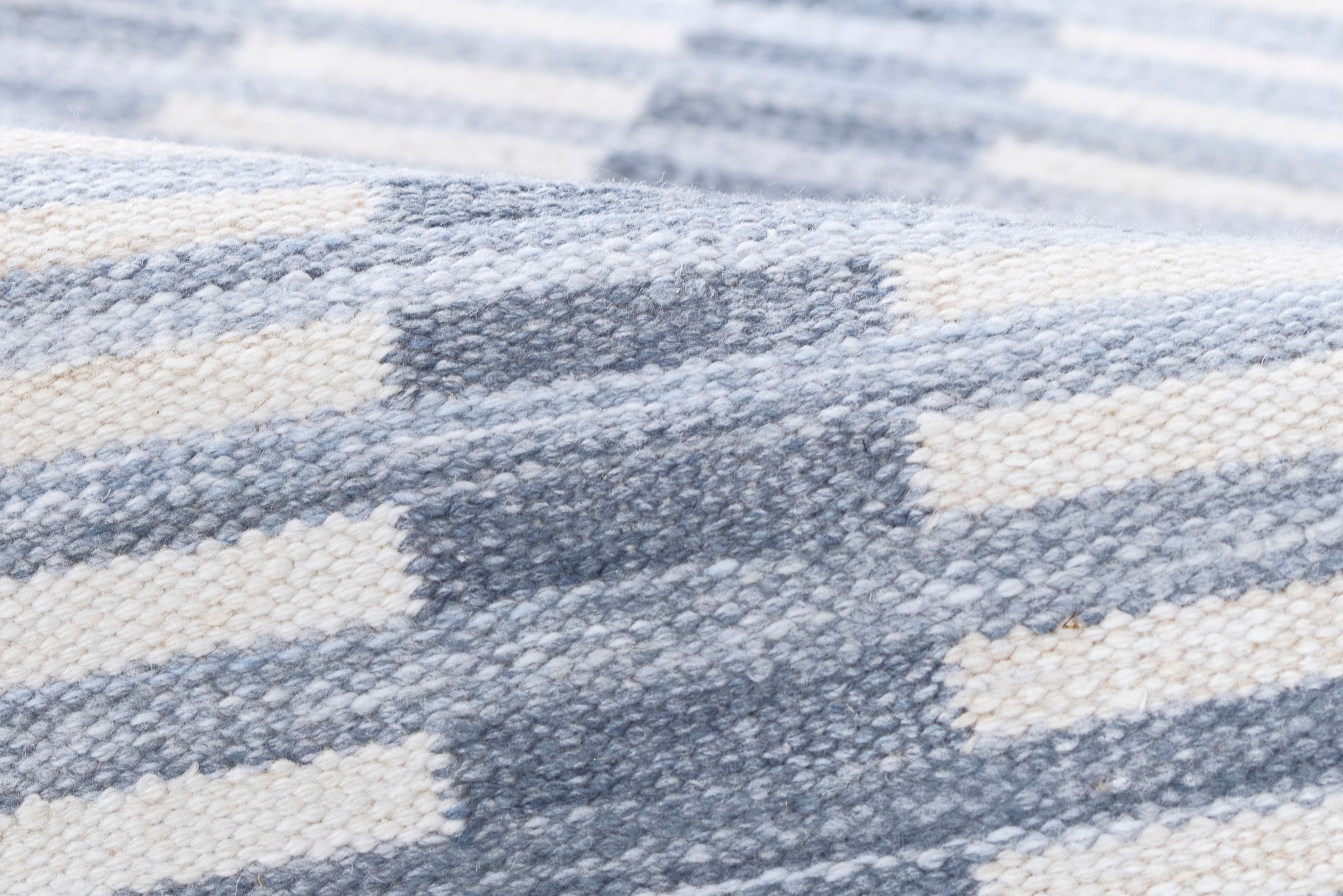 Blue-gray and cream striped chunky-knit blanket throw, close-up of woven texture.