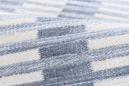 Blue-gray and cream striped chunky-knit blanket throw, close-up of woven texture.
