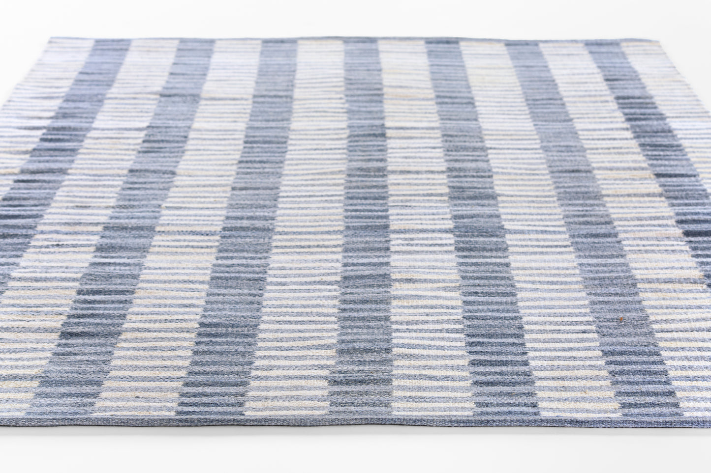 Rectangular woven runner rug with navy, light blue and ivory stripes, modern coastal style.