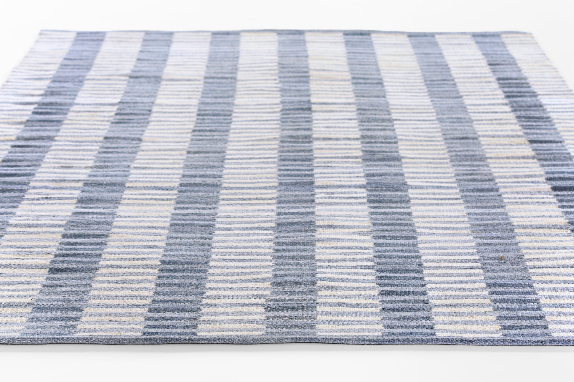 Rectangular woven runner rug with navy, light blue and ivory stripes, modern coastal style.