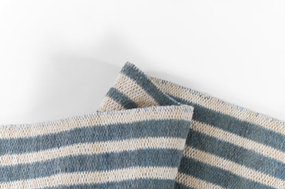 Blue and beige striped woven cotton rug with a chunky weave texture, folded pieces.
