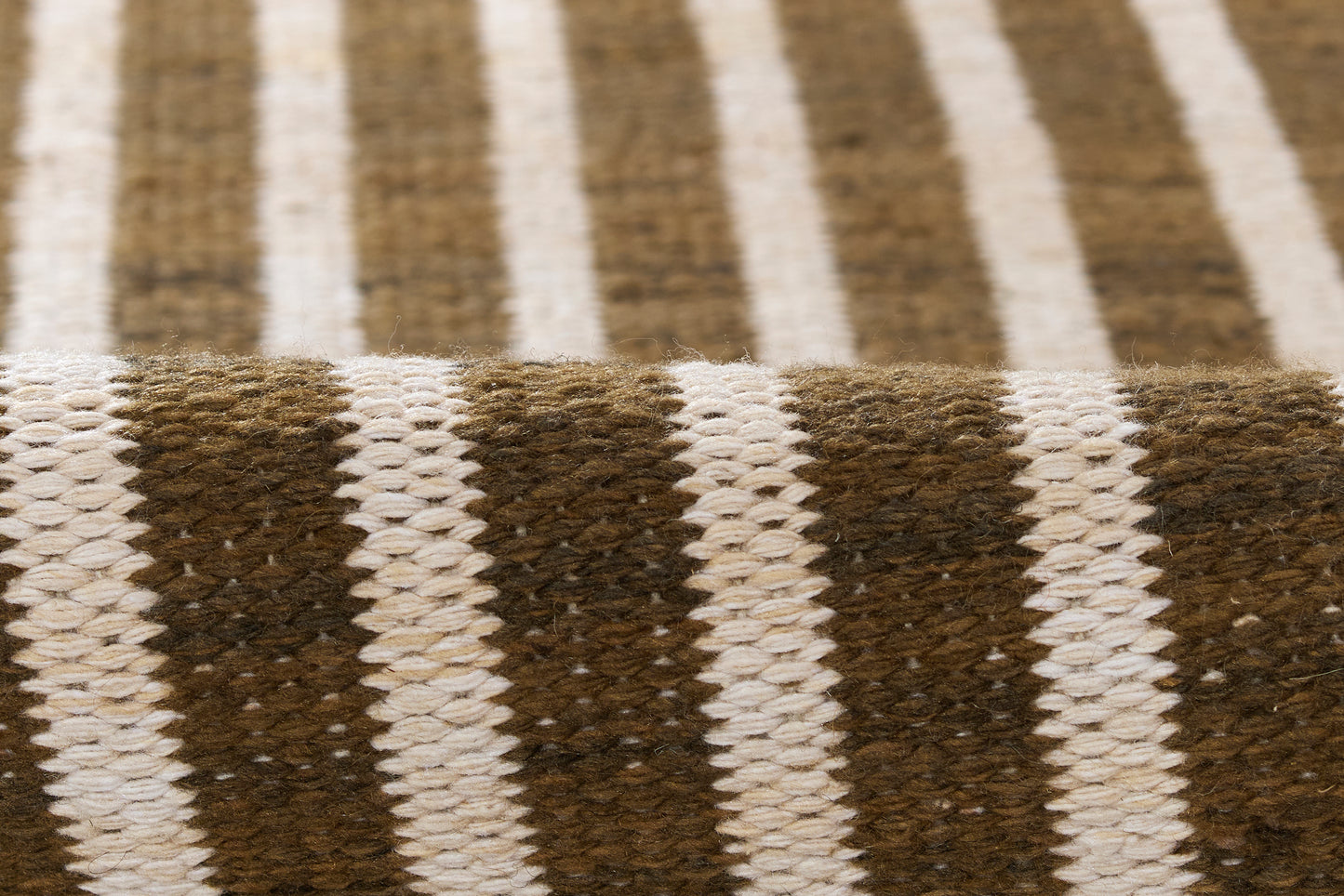 Brown and white striped woven rug with chunky texture and rustic cozy vibe.