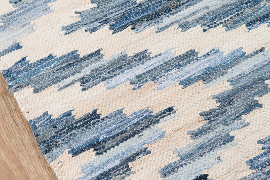 Blue and cream zigzag woven rug in denim tones on wood floor; textured, casual coastal area rug.