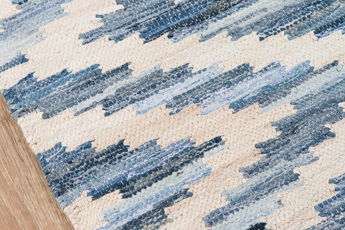 Woven runner rug with blue zigzag stripes on a beige background; indigo to light blue tones, flatwoven kilim style, 2' x 8'.