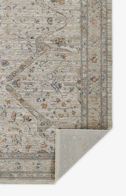 Beige traditional floral area rug with blue-gray vines and rust accents, ornate border; folded corner reveals backing.