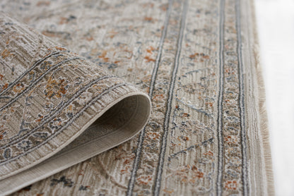 Beige oriental rug with blue and orange floral motifs, woven texture, rolled corner and fringe.