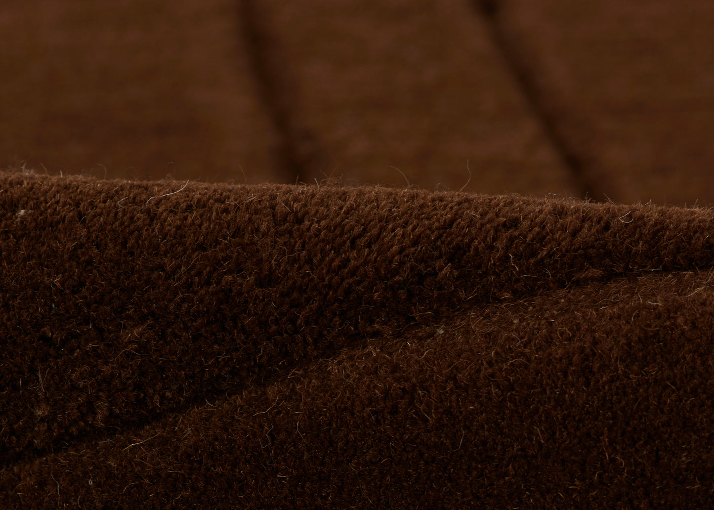 Close-up of chocolate brown rug fibers with a soft, plush texture.