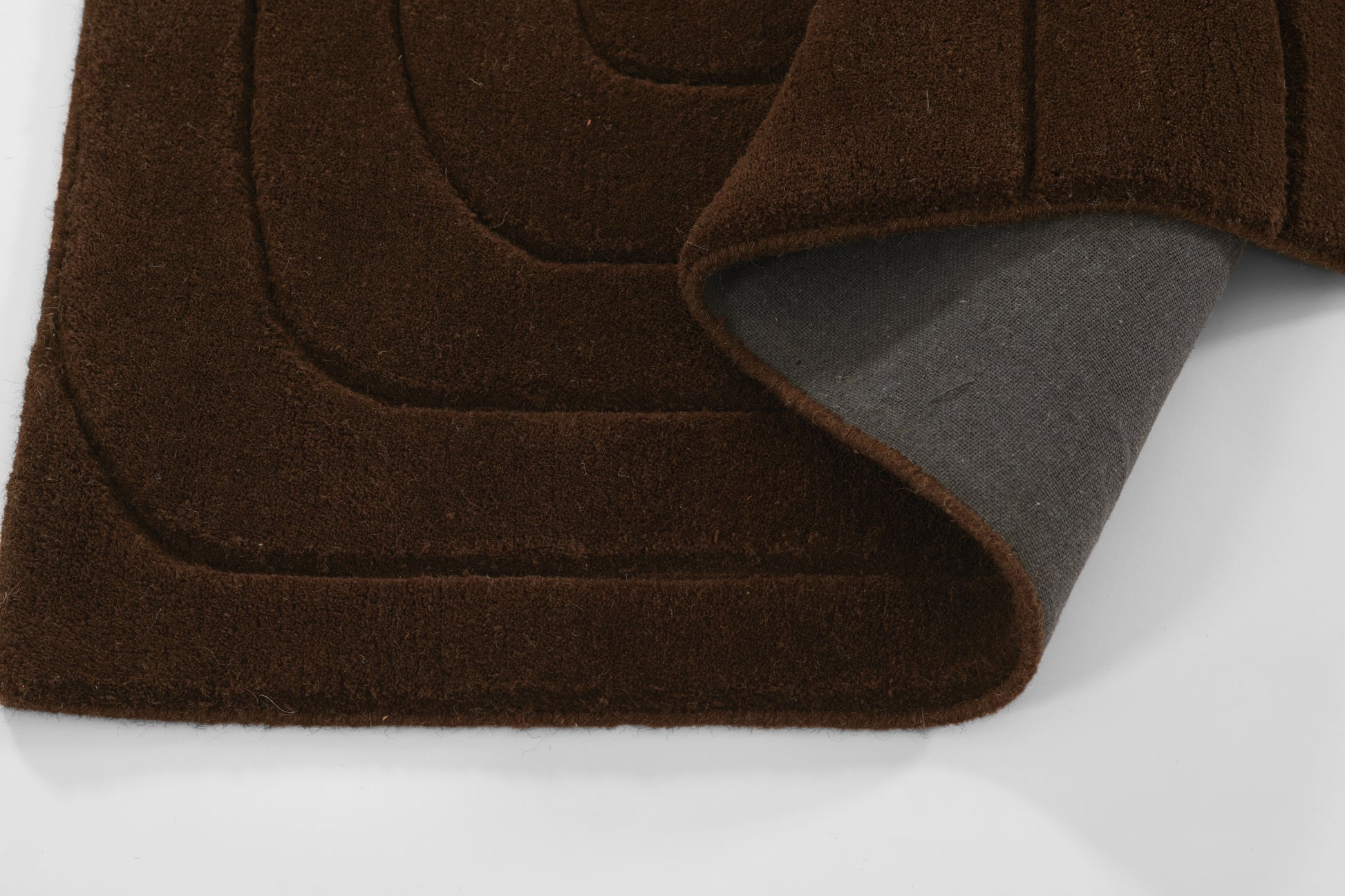 Brown shag rug with layered curved panels and gray underside peeking out.
