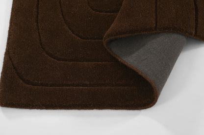 Brown shag rug with layered curved panels and gray underside peeking out.