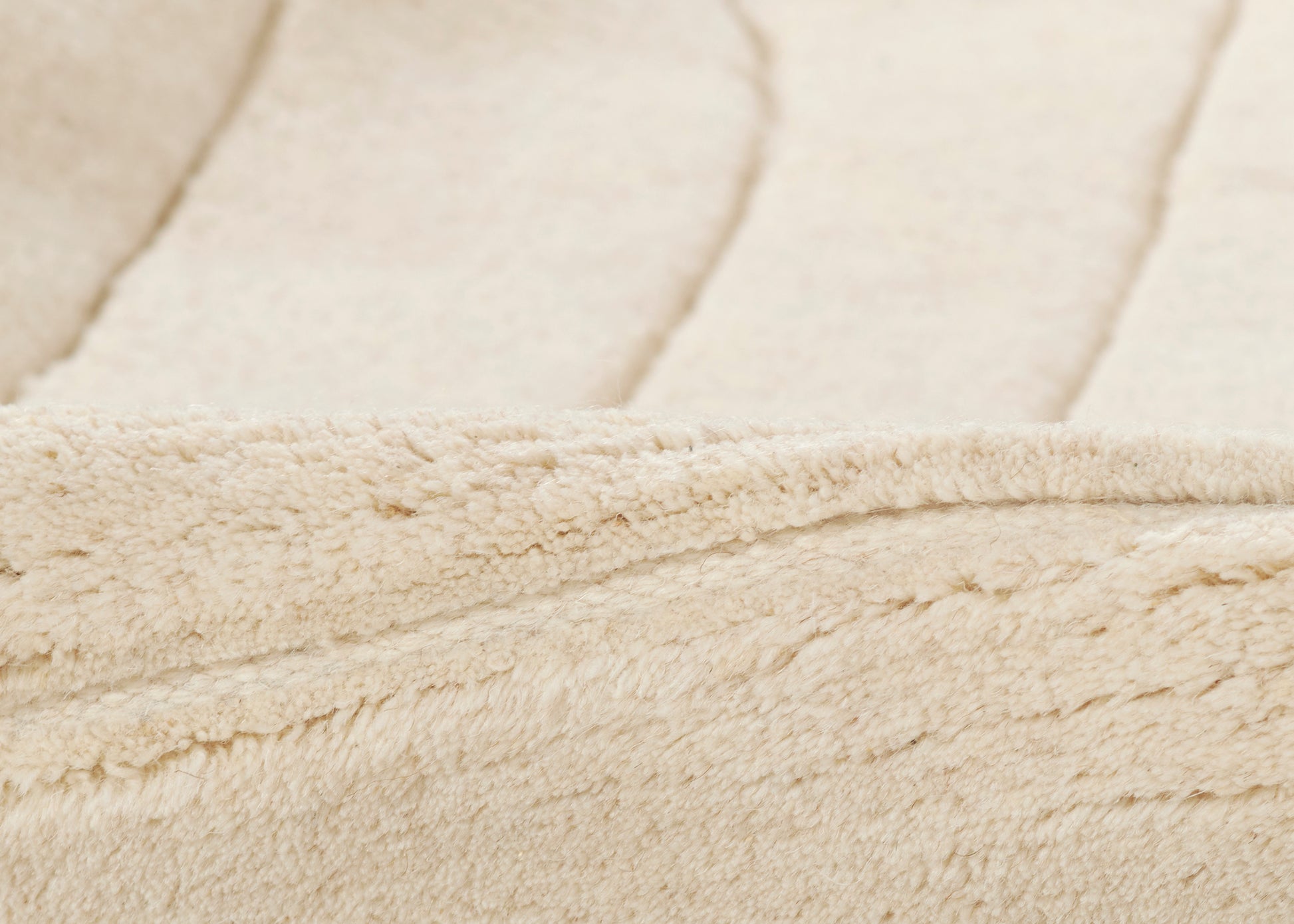 Beige faux shearling coat lining with plush sherpa pile and stitched edge detail.