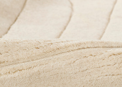Cream sherpa fleece fabric close-up with plush texture and folded seam edge.