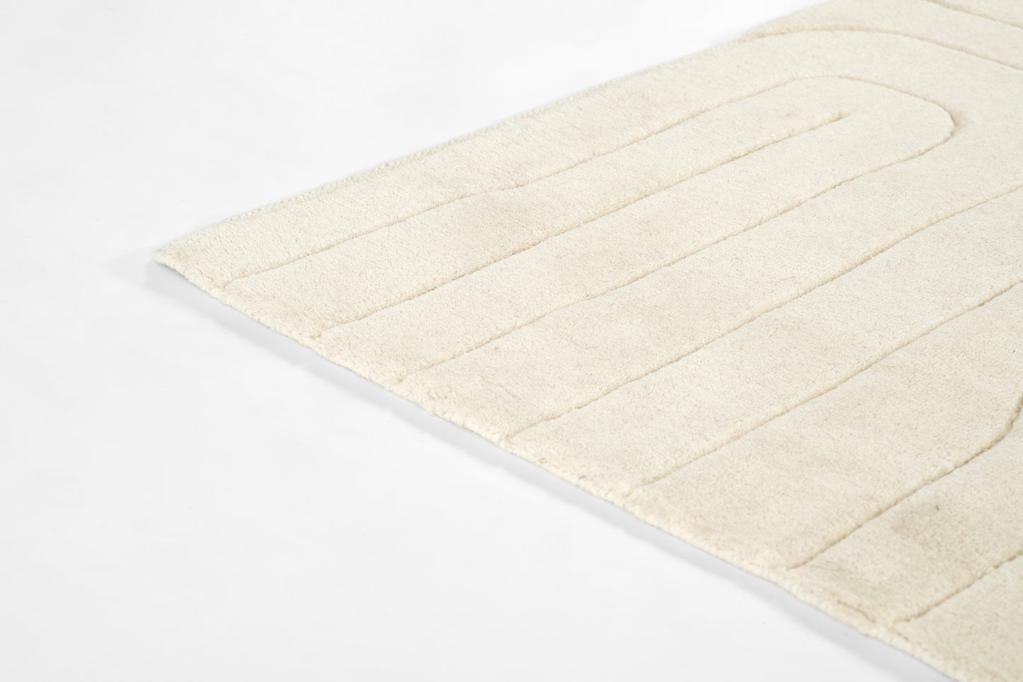 Ivory plush bath rug with horizontal channel seams, soft terry texture and a rectangular shape.