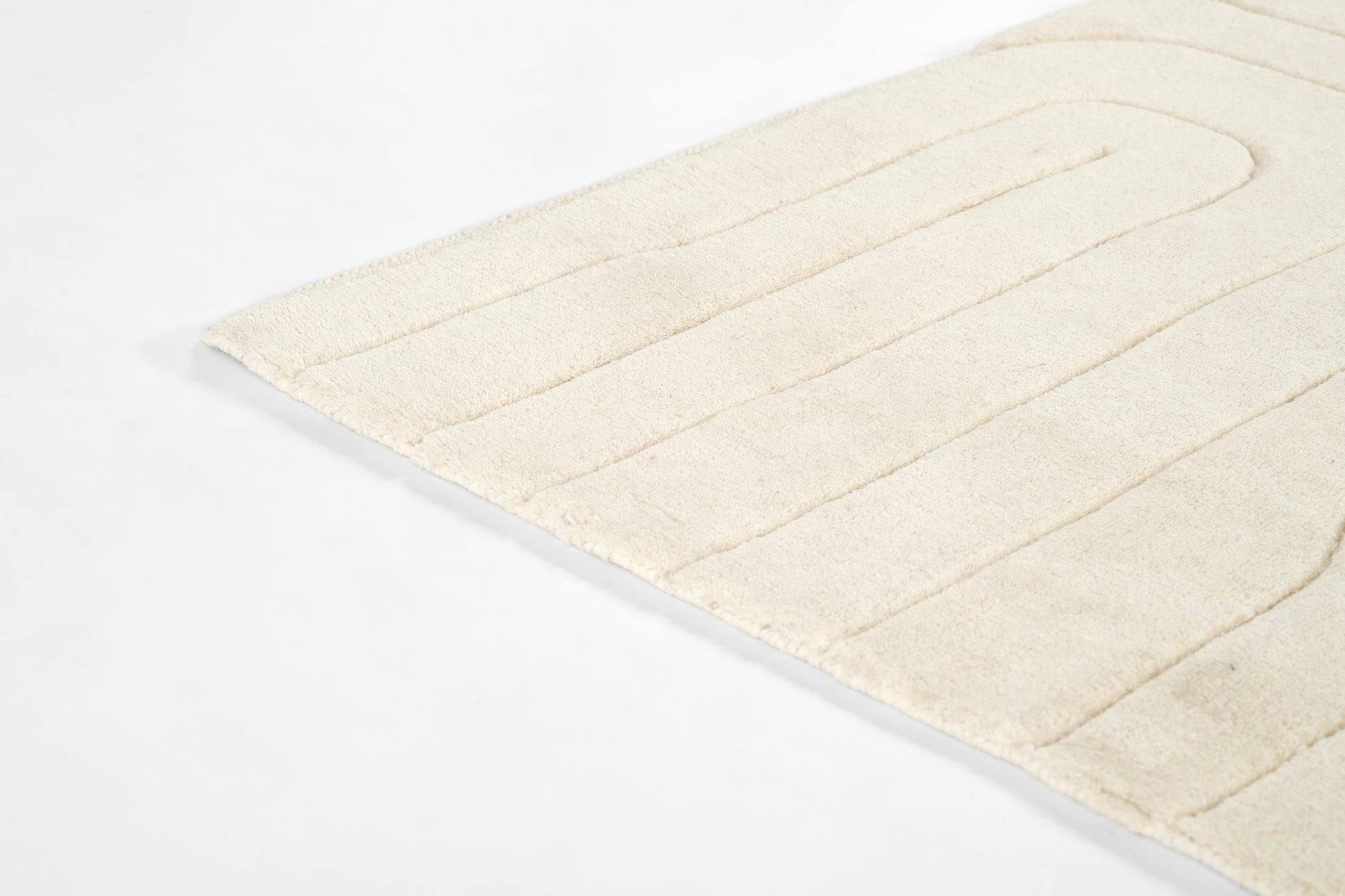 Cream ivory plush bath mat with ribbed rectangular sections, soft cotton texture.
