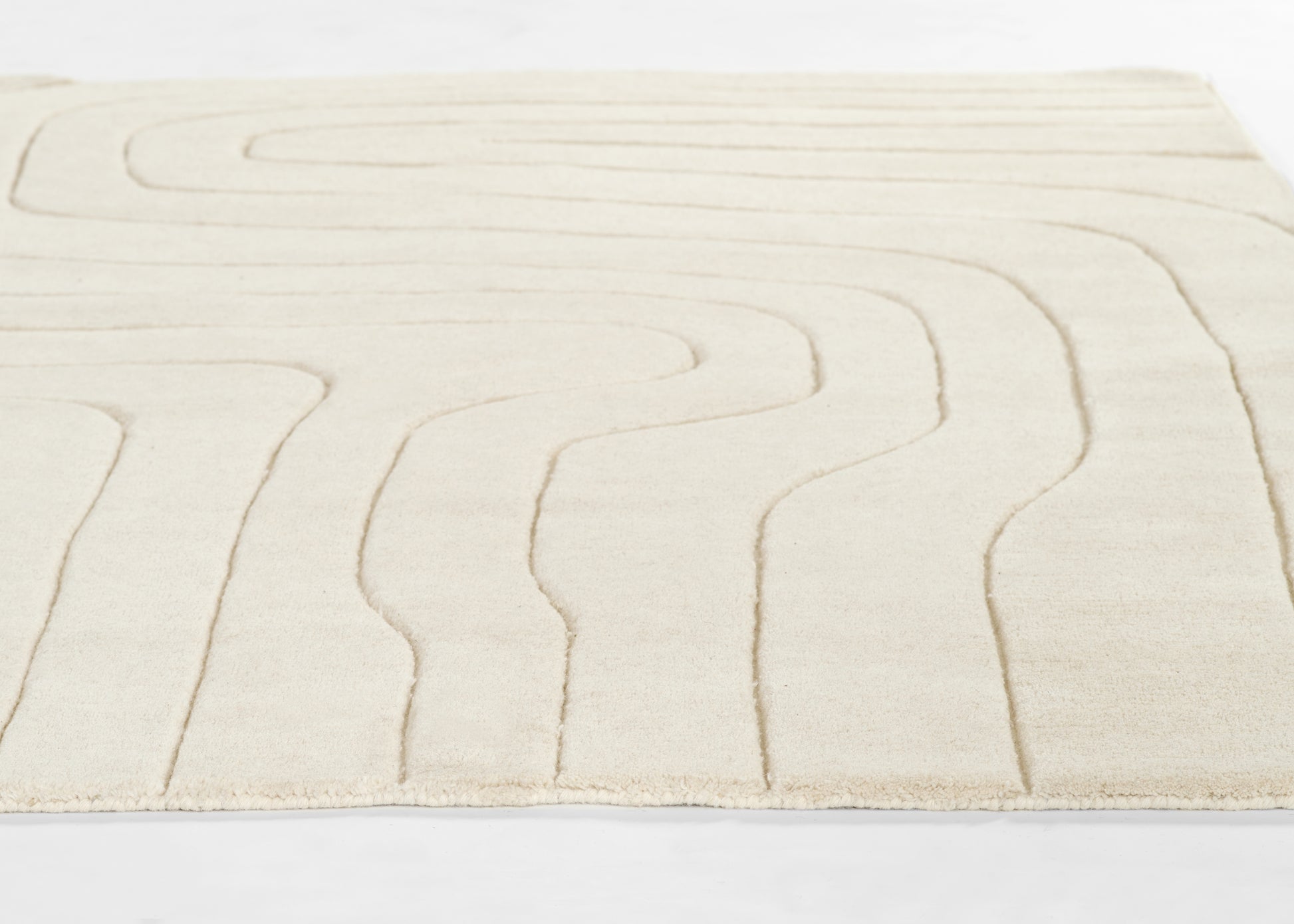 Ivory rug with cream raised lines forming abstract curved pattern; soft plush pile, rectangular living-room mat.