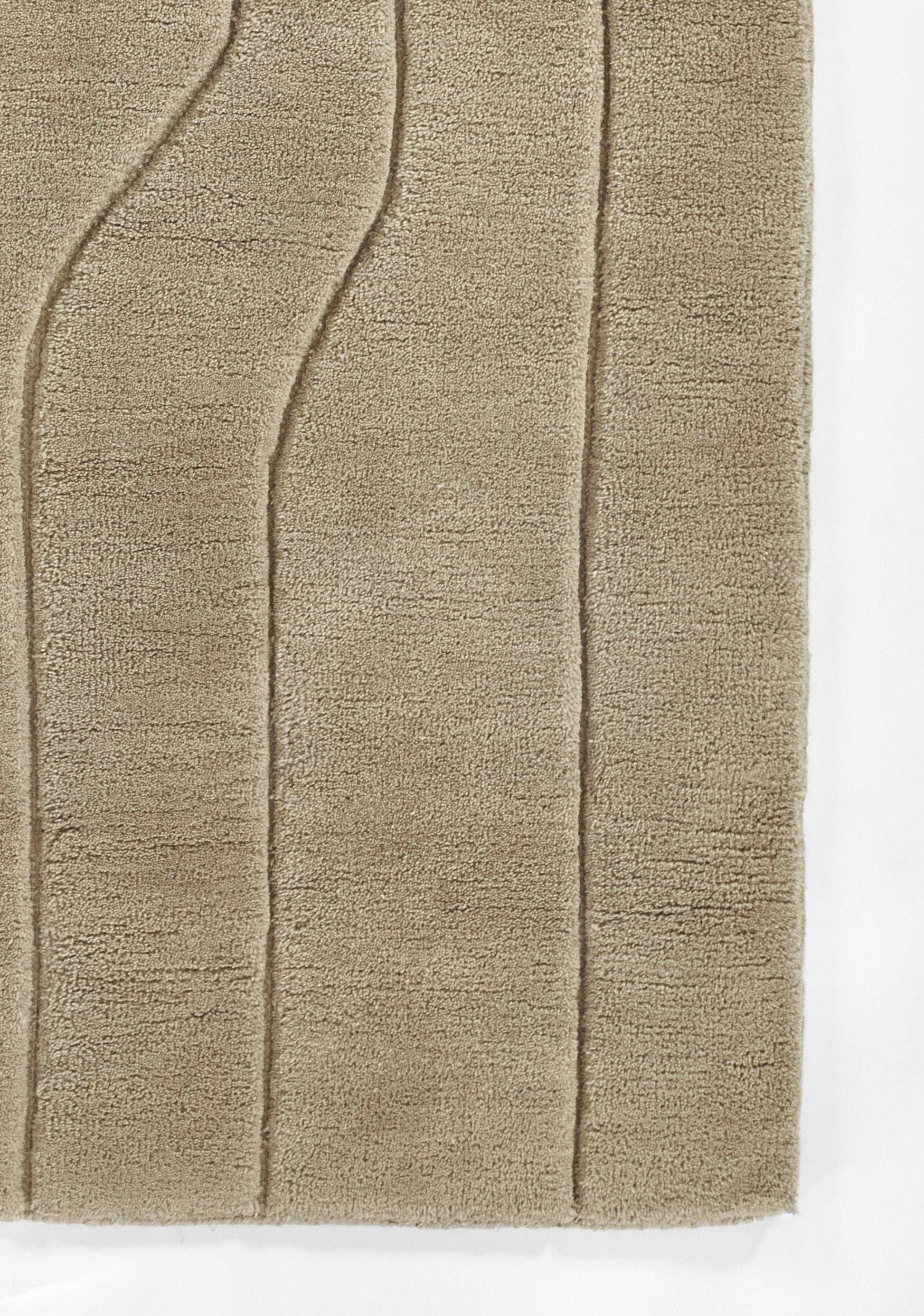 Beige plush bath rug with tufted vertical curved lines and soft chenille texture.