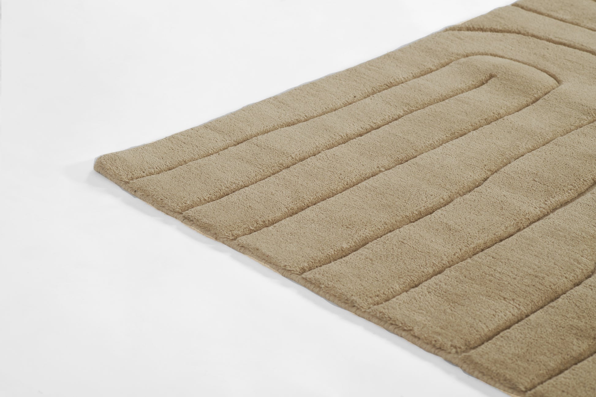 Beige plush rug with parallel ribbed stripes and soft shag texture, rectangular floor mat.