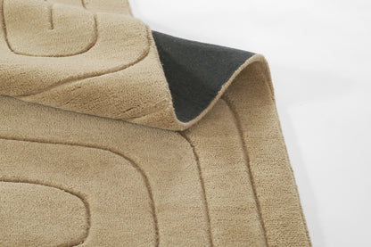 Beige plush rug with curved stitched border, soft sherpa texture; dark reverse side visible.