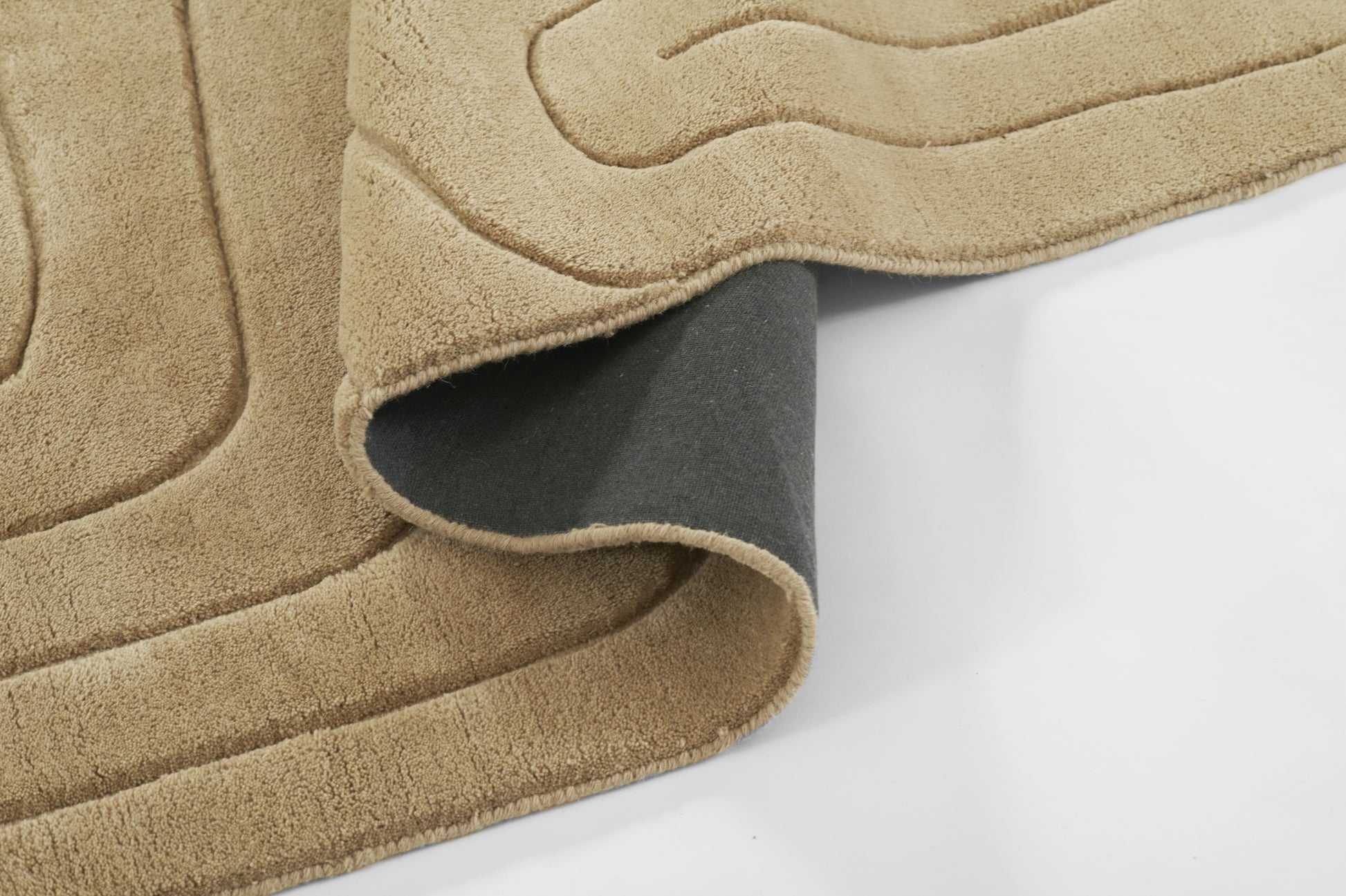 Beige plush throw blanket with curved quilted pattern, dark gray backing visible for cozy decor.