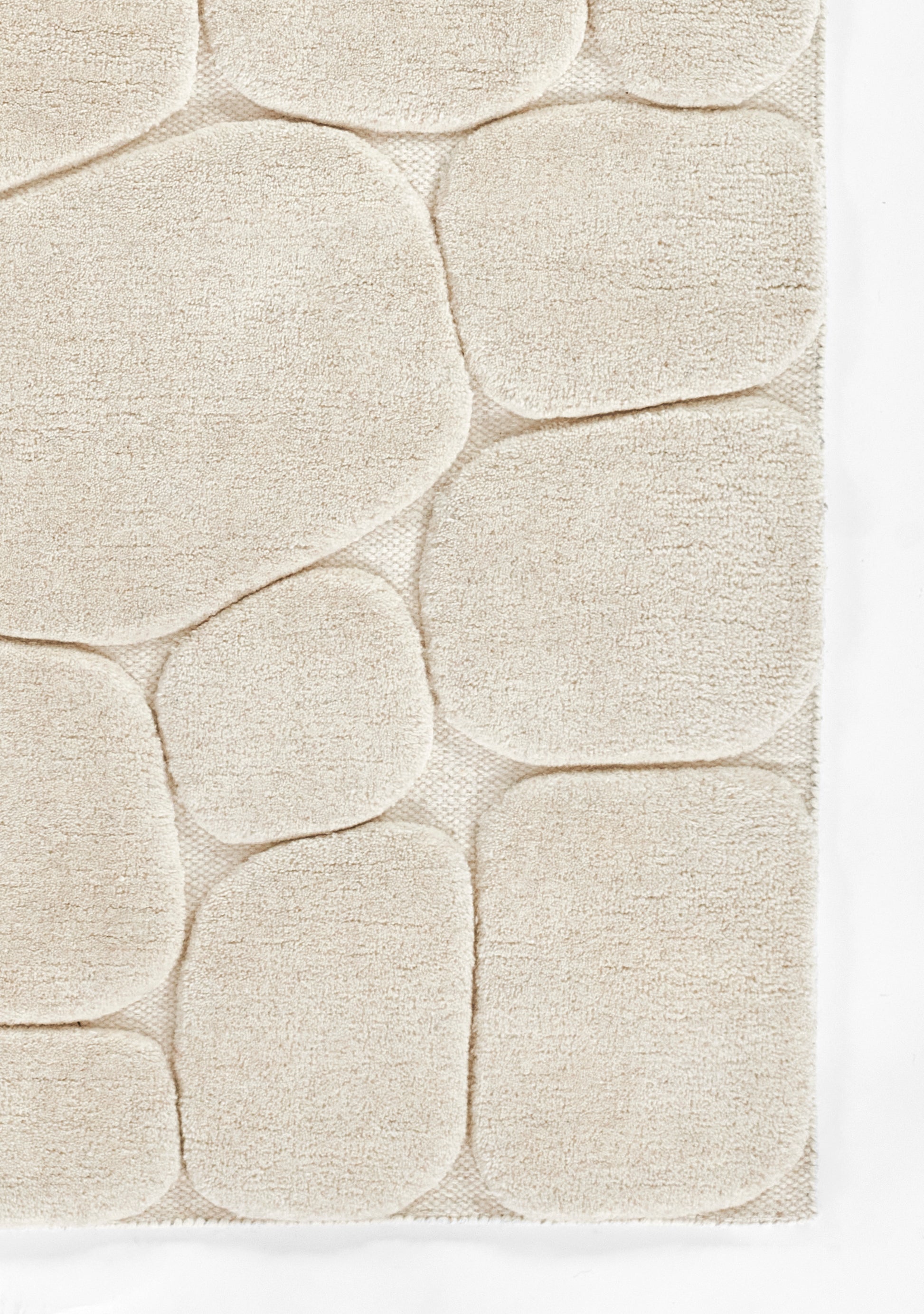 Cream tufted rug with pebble-shaped, rounded blocks; plush pile for modern, cozy interiors.