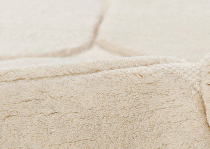 Beige sherpa fleece fabric close-up with folded edge and soft, fluffy pile.