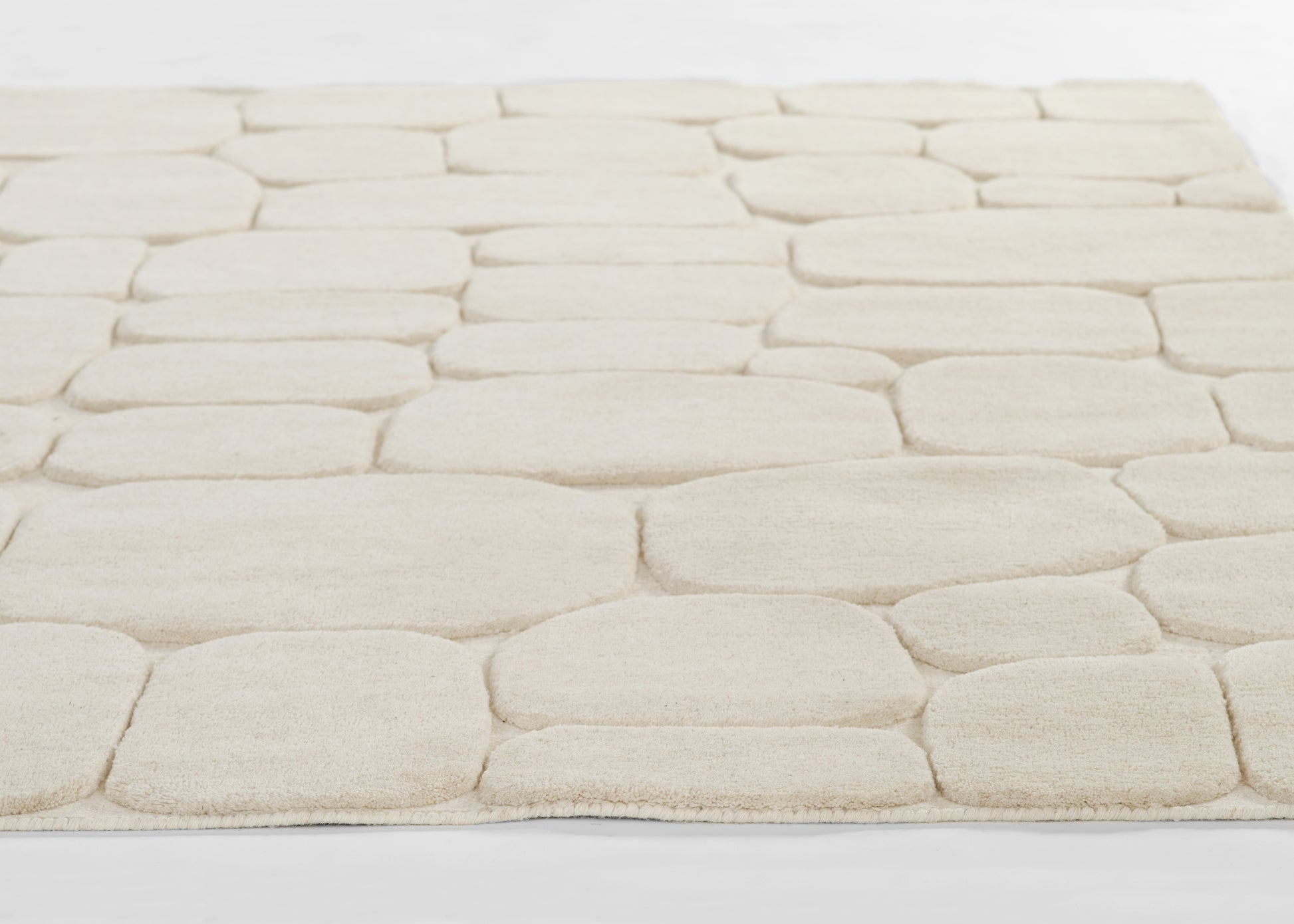 Cream tufted rug with large rounded-square blocks in a stone-like pattern; soft plush pile.