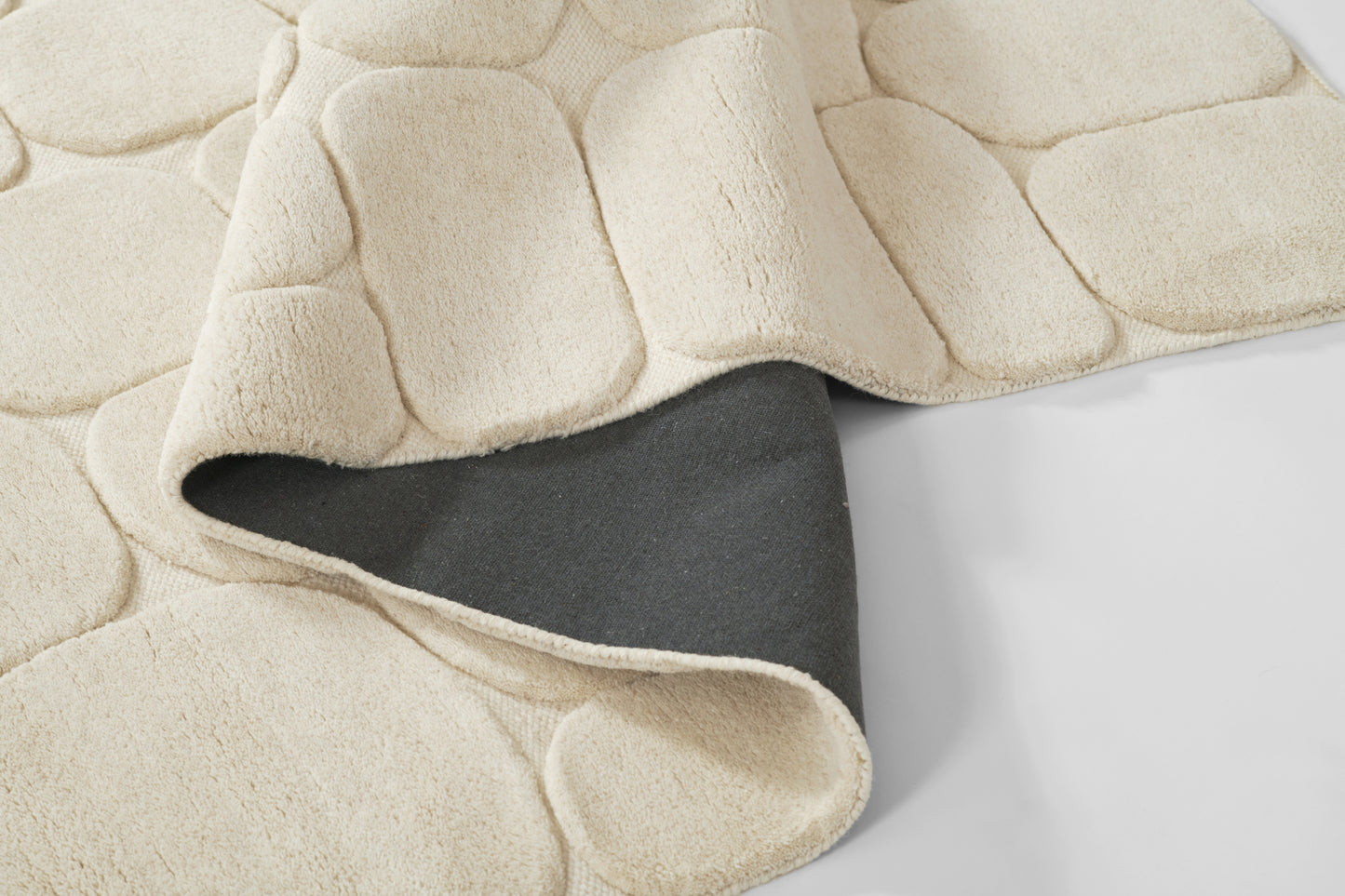 Beige plush quilted throw with large square panels and dark grey underside showing at corner.