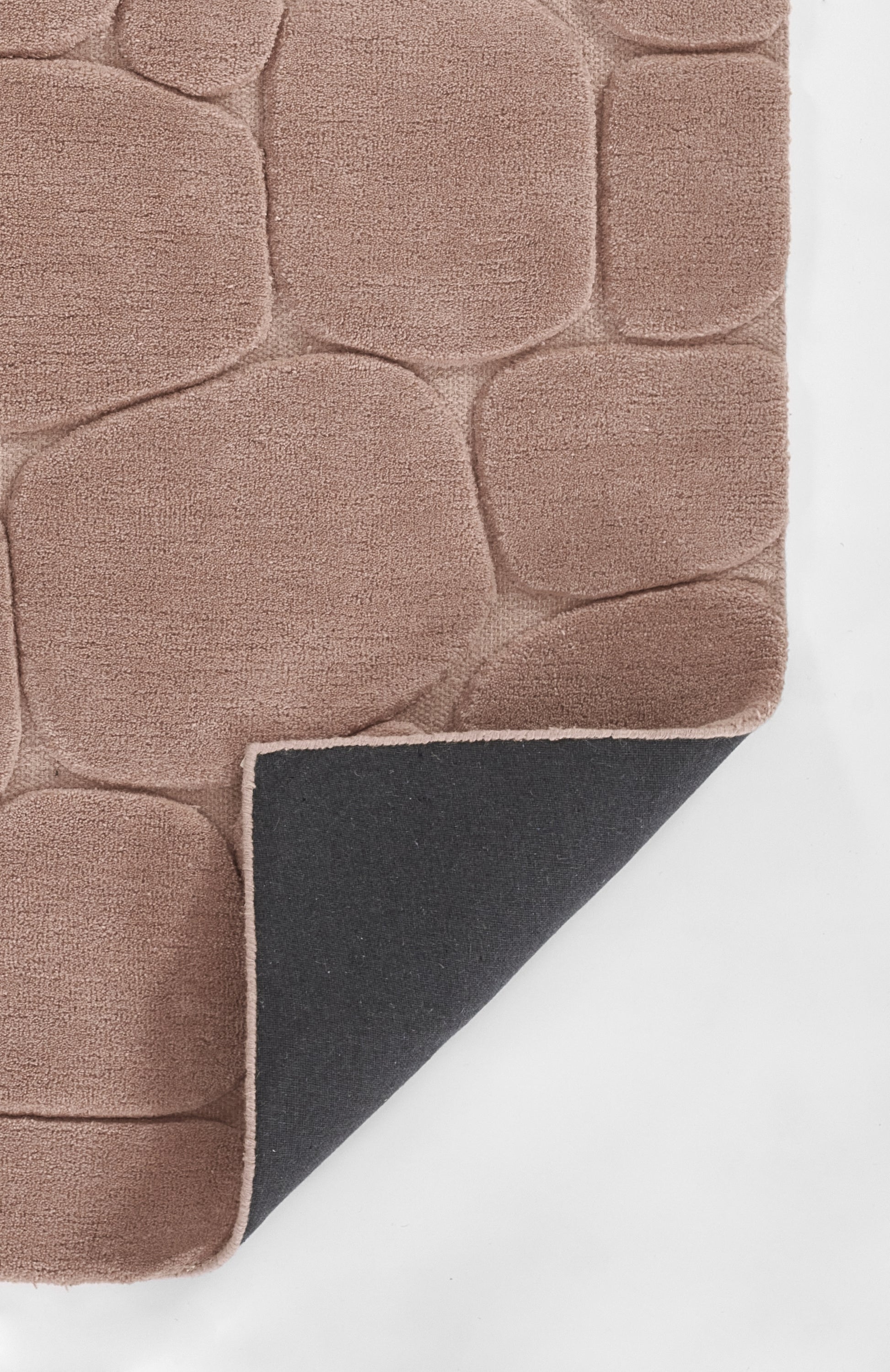 Soft pink shag rug with pebble-like square panels; corner folded to reveal black backing with pink trim.