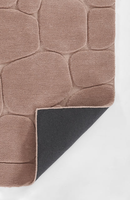 Pink-beige tufted rug with rounded square block pattern; soft pile, folded corner reveals dark underside with pink edge.