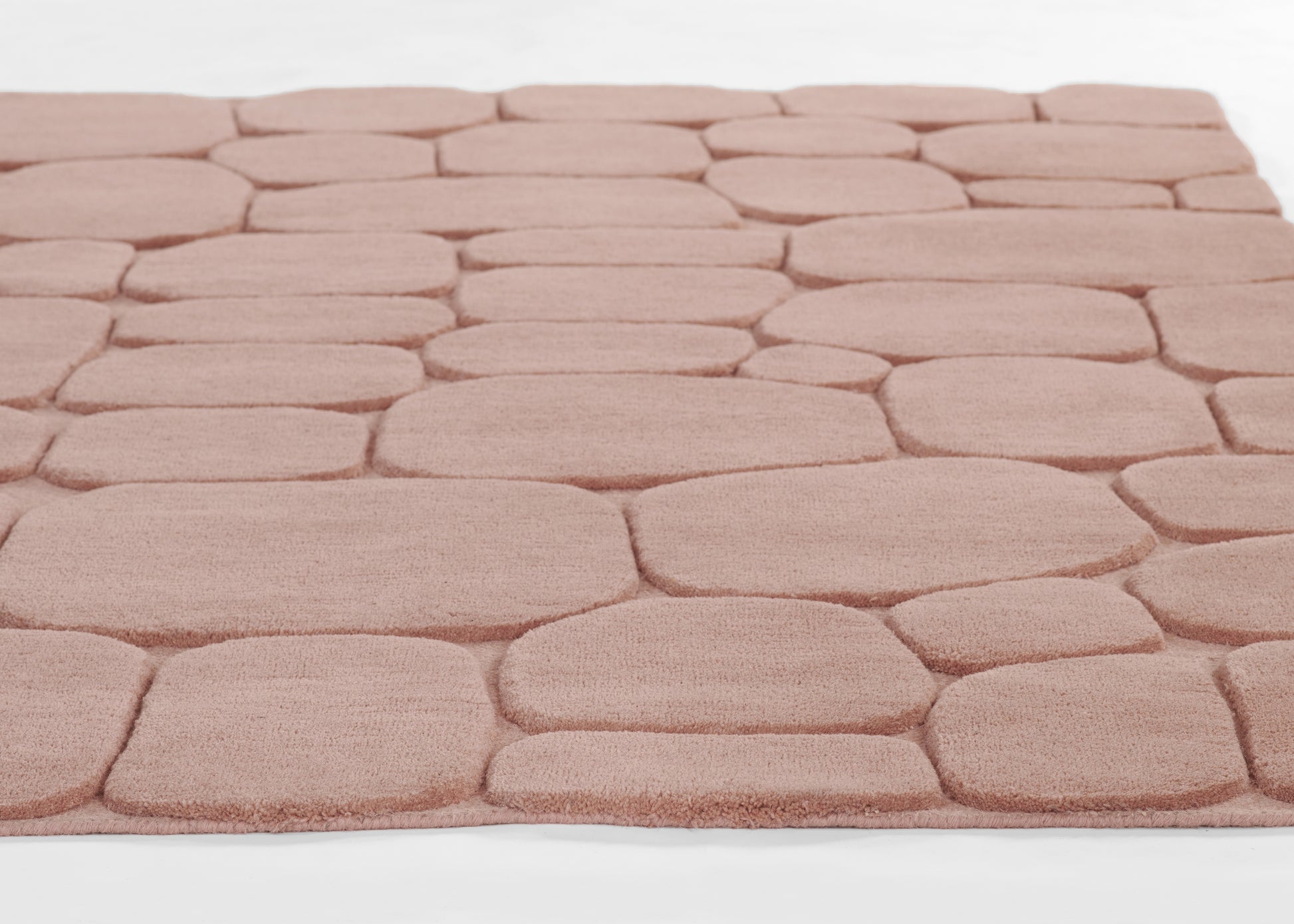 Soft pink pebble-pattern rug with plush, rounded stone-like squares for cozy decor.