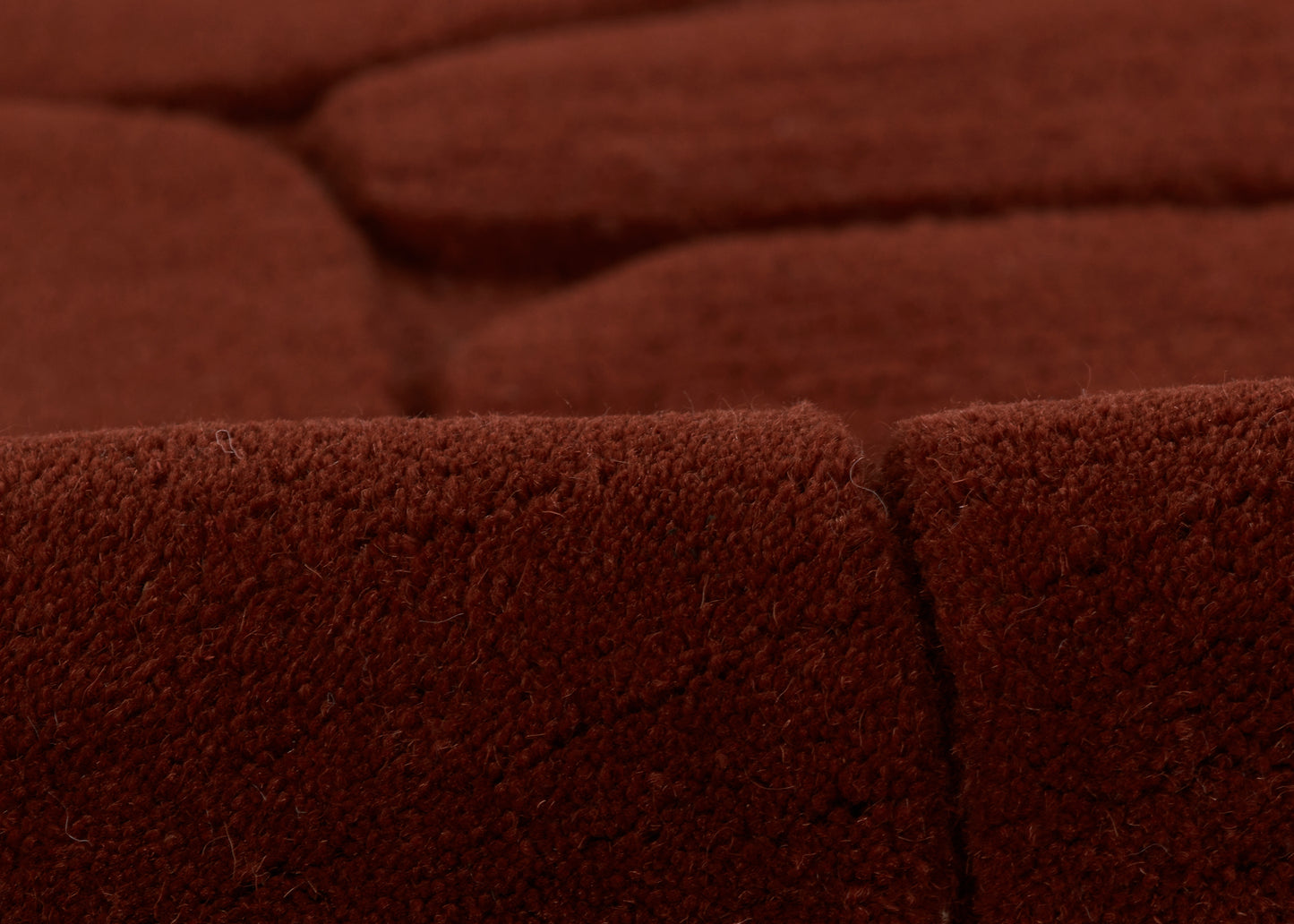 Burnt red velvet upholstery with soft pile, close-up of seam on a plush sofa cushion